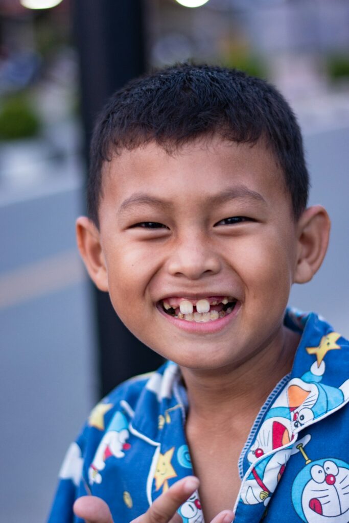 A young boy grinning widely, showing a gap where his front baby teeth have come out.