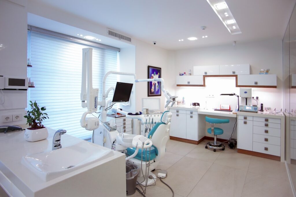 A bright treatment room with daylight coming through blinds and equipment along one wall.