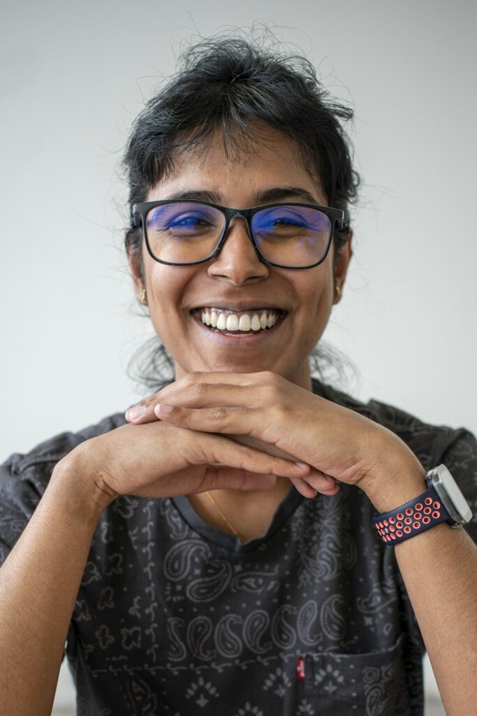 Dr Nayomi, the dentist at Aster Dental Studio, smiling with her chin resting on her hands.