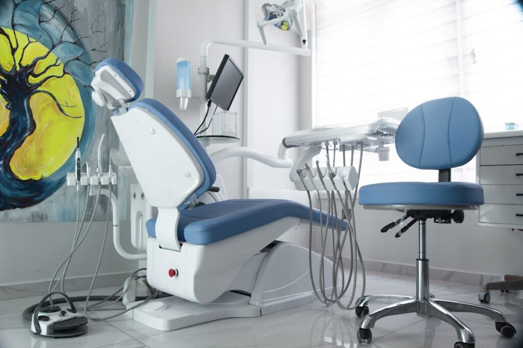 A blue and white dental chair with instruments arranged beside it.